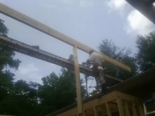 Carpenter setting a ridge beam over a new addition frame — Ice Dam Removal by Roofing Brothers in Oyens