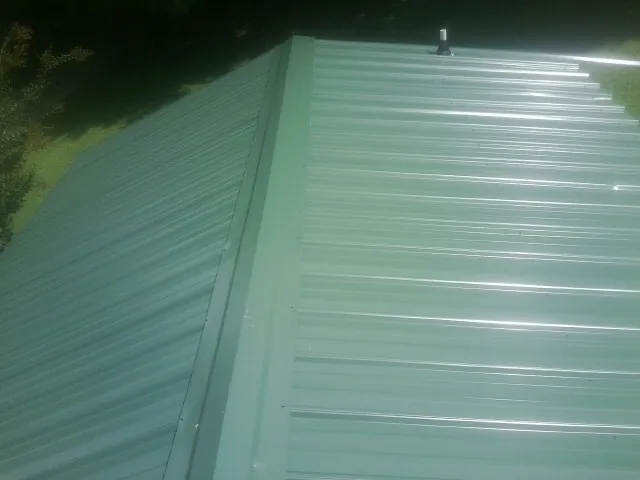 New green metal panels meeting at the ridge of a roof — Flat Roof Repair work by our crew in Oyens