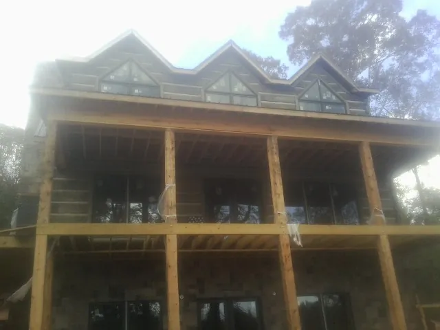 Dormers and porch framing on a large log home under construction — Roof Coating work by our crew in Oyens