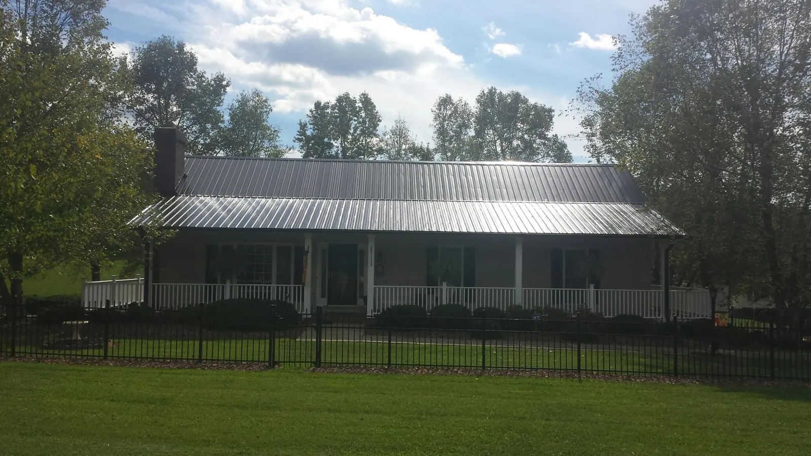 Gray metal roof on a brick ranch with a full width front porch in Oyens