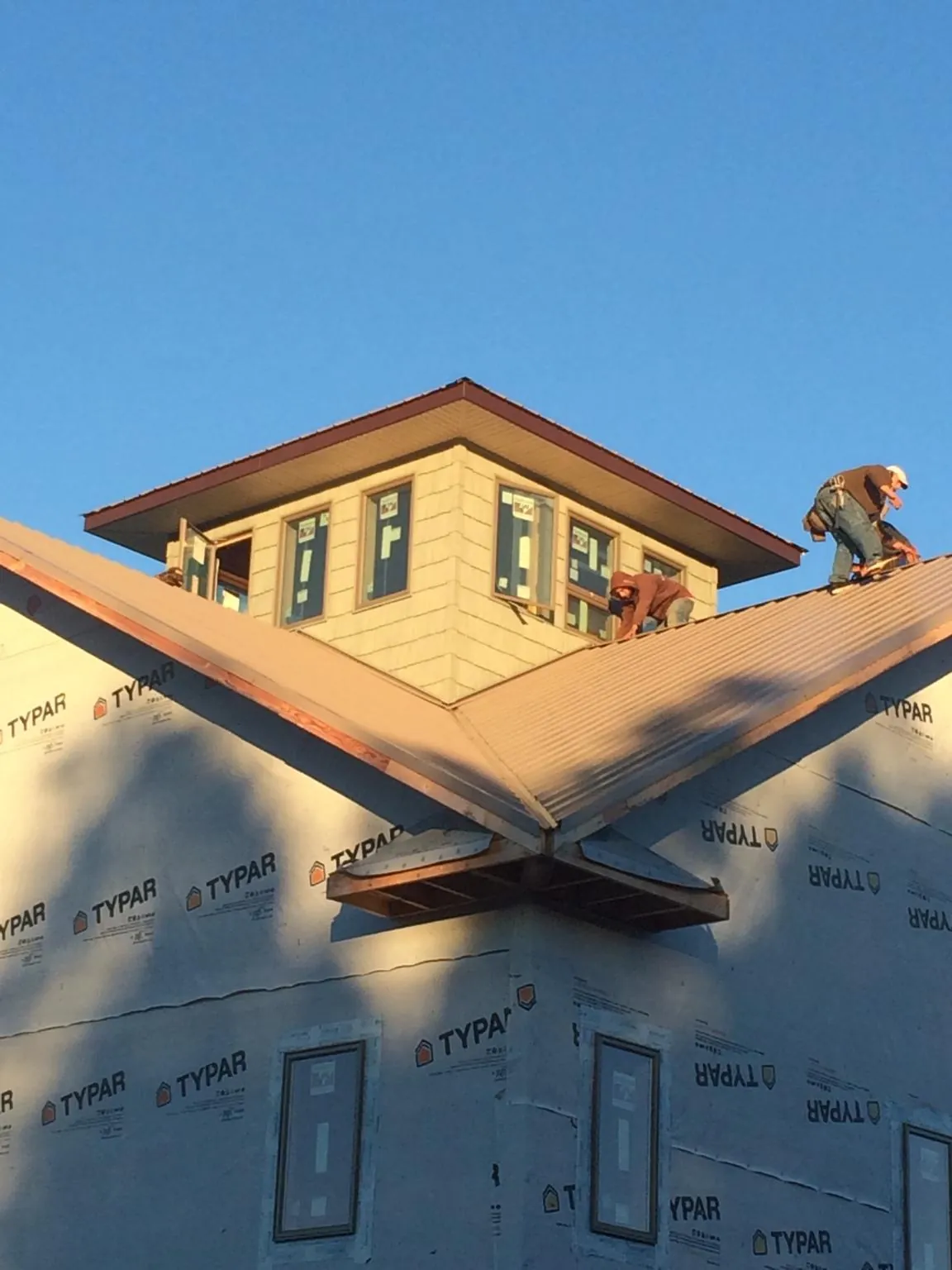 Roofers working around a rooftop cupola on a new metal roof at sunset — Roof Waterproofing in Oyens by Roofing Brothers